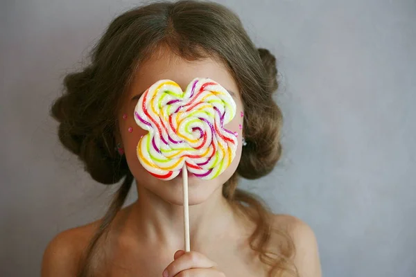Seorang Gadis Memegang Lollipop Berwarna Warni Pada Tongkat Depan Wajahnya — Stok Foto