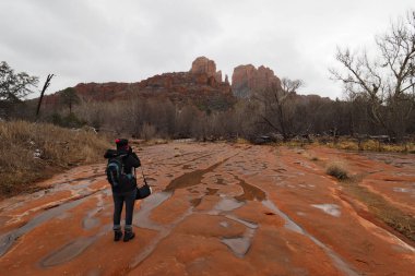 Sedona, Arizona 'nın dışındaki Red Rock State Park' ta Katedral Rock 'ta karlı bir kış gününde fotoğraf çeken bir kadın..