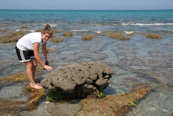 Young woman explores tide pools and rock formations of Coral Cove Park in Tequesta, Florida.