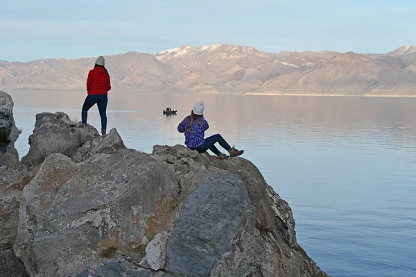 Dua wanita muda menikmati pemandangan Danau Piramida yang tenang, Nevada dari formasi batu di pantai . — Stok Foto