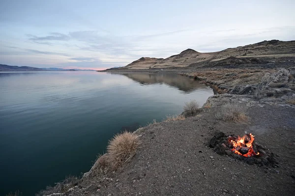 Api unggun pada formasi batuan yang menghadap ke Danau Piramida, Nevada dengan danau di latar belakang . — Stok Foto