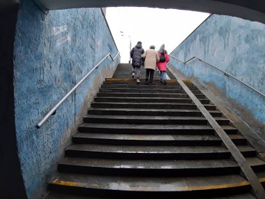 Büyükanne ve torunlar alt geçitte merdivenleri çıkıyorlar.