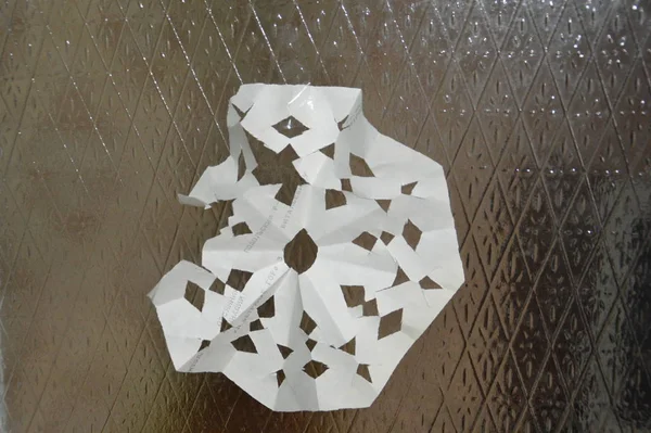 Płatki śniegu wycięte z białego papieru wiszą na szklanych drzwiach — Zdjęcie stockowe