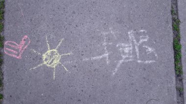 Kaldırımda tebeşirle çizilmiş çocuk resimleri.