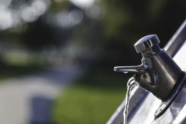 Wasserhahn aus Metall im Park in der Sonne an einem Sommertag mit fließendem Wasser — Stockfoto