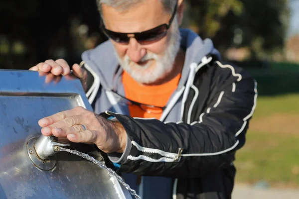 Man at drinking fountain in nature — Stock Photo, Image