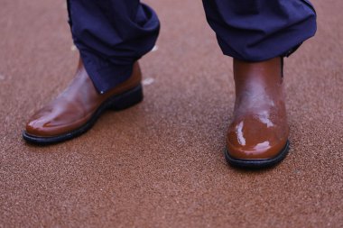 Mavi pantolon ve kırmızı çizmeler kırmızı çimento üzerinde duran adam