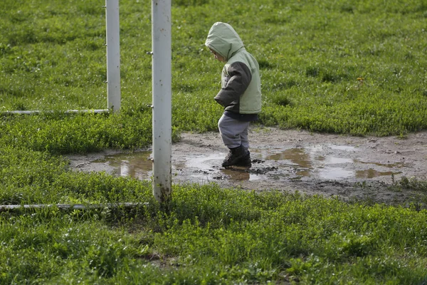 Два года ребенок ходит и играет в грязной луже — стоковое фото