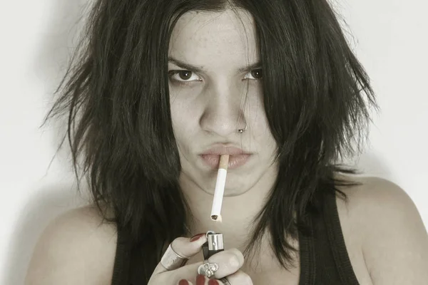 Jeune brunette fronçant les sourcils foudre une cigarette — Photo