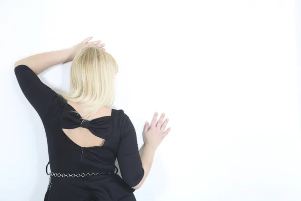 Femme blonde capturée par derrière s'appuyant sur un mur blanc — Photo