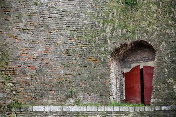 Entrée de forteresse vieillie avec porte métallique rouge — Photo