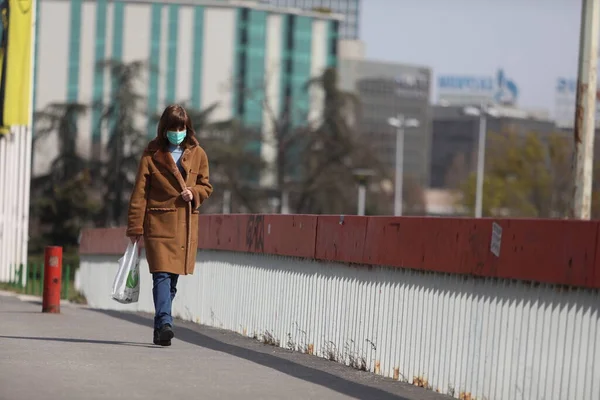 Belgrade Serbia 2020年3月28日 マスクをした女性が通りを歩く コロナウイルスがセルビア全土に広がり続ける中で 人々が外に出ることができる日の間に 政府はコロナウイルス病の蔓延を防ぐために夜間外出禁止令を課した ストック写真