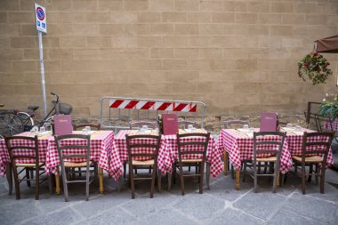 Sokakta kırmızı kare kapaklı restoran masaları