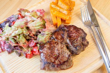 Taze kavrulmuş kemikli biftek ve tatlı patates ve karışık salata.