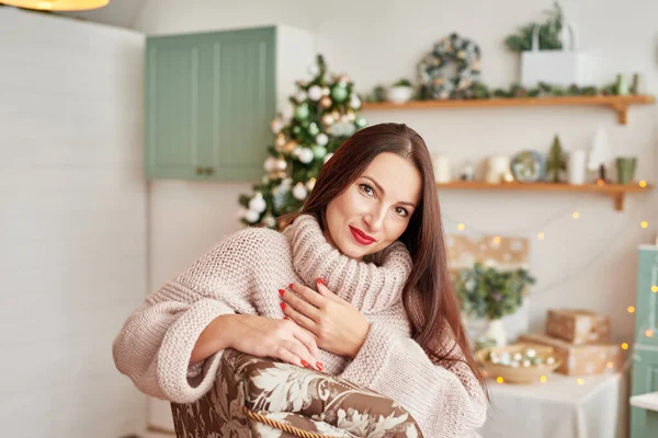 Gyönyörű nő meleg ruhákban a karácsonyfa hátterében. Nagyon szép lány mosolyog, közelről. Boldog fiatal hölgy a karácsonyfa mellett. Újévi koncepció.Fiatal lány karácsonyfa háttér — Stock Fotó