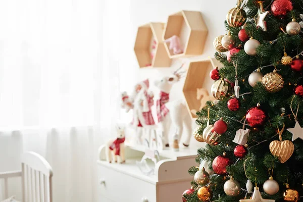 Regal mit Weihnachtsfiguren Weihnachtsmann und Hirsch im Kinderzimmer. Weihnachtsstimmung im Kinderzimmer. Neujahrsdekor und Baum im Kinderspielzimmer. Weihnachten im Kinderzimmer. — Stockfoto