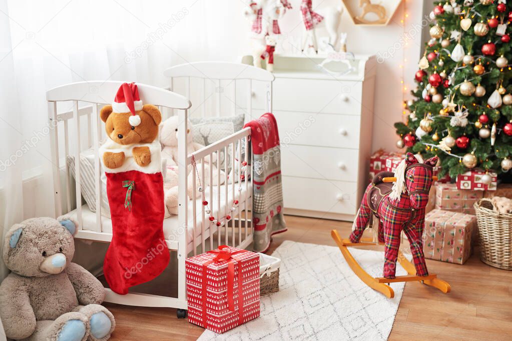Christmas nursery, Christmas decor in children's bedroom, children's playroom decorated for new year, white children's bedroom, Christmas toys and gifts in children's bedroom, white bed with soft toys