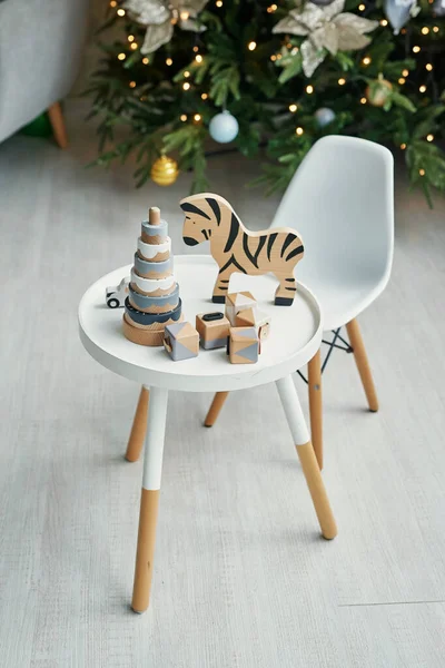 Scandinavian children furniture. Scandinavian children\'s room with a Christmas tree, table, chair and wooden educational toys. The interior of children\'s room in the loft style.