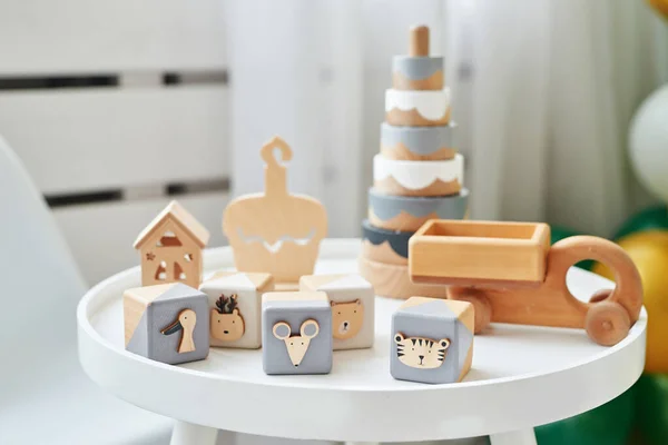 Scandinavian children furniture. Scandinavian children\'s room table and wooden educational toys. The interior of children\'s room in the loft style. Wooden toys cubes, pyramid and car.