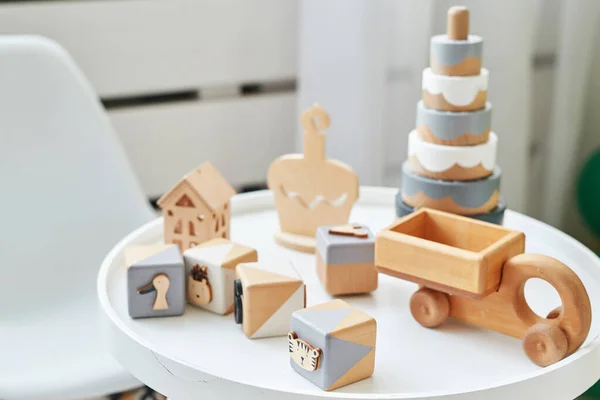 Scandinavisch kindermeubilair. Scandinavische kinderkamer tafel en houten educatief speelgoed. Het interieur van kinderkamer in zolderstijl. Houten speelgoedblokjes, piramide en auto. — Stockfoto