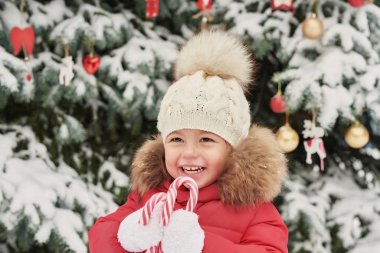 Kış ormanındaki kız. Komik bebek kış günü dışarıda gülüyor. Kar parkında mutlu kış kızları. Kış ormanlarında ya da parkta Noel. Noel ağacı arka planında bir Noel bebeği. Şekerli çocuk