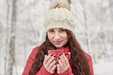 Kadınlar kış sabahı Cozy Snowy House Garden 'da sıcak çay ya da kupadan kahve içer. Güzel kız, bir bardak ılık içecekle kışın tadını çıkarıyor. Noel tatilleri. Sıcak kış yaşam tarzı.