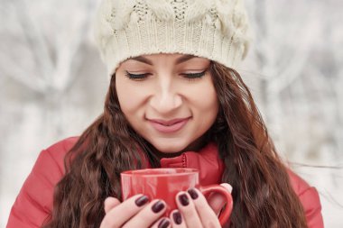 Kadınlar kış sabahı Cozy Snowy House Garden 'da sıcak çay ya da kupadan kahve içer. Güzel kız, bir bardak ılık içecekle kışın tadını çıkarıyor. Noel tatilleri. Sıcak kış yaşam tarzı.