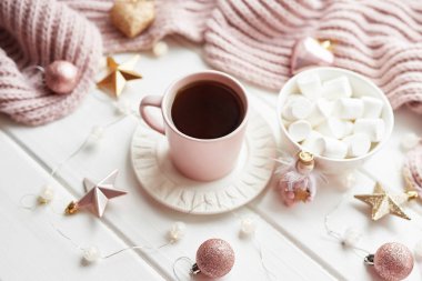 Noel dekoru, balolar, arka planda yün ekose kumaşlar, ev konforu, mevsimsel kış kutlamaları. Kart Şablonu. Marşmelovlu pembe bir Noel bardağı..