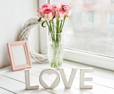 Sevgililer günü kartı. Taze güller ve pencere pervazında fotoğraf çerçevesi olan kompozisyon. Mesaj için yer var. Üzerinde 