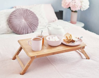 Otel odasında, yatakta kahvaltı. Kalacak yer. Yatakta kahvaltı, çay fincanı, tepside krep ve yatak arkası manzarası. Uzayı kopyala Romantik Sevgililer Günü kahvaltısı. Sıcak kahvaltı Maslenitsa