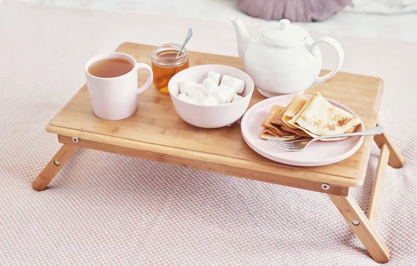 Frühstück im Bett im Hotelzimmer. Unterkunft. Frühstück im Bett mit Teetasse mit Pfannkuchen auf Tablett auf Bett Hintergrundansicht. Kopierraum. romantisches Valentinstagsfrühstück. gemütliches Frühstück maslenitsa — Stockfoto