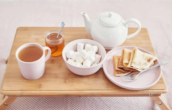 Frühstück im Bett im Hotelzimmer. Unterkunft. Frühstück im Bett mit Teetasse mit Pfannkuchen auf Tablett auf Bett Hintergrundansicht. Kopierraum. romantisches Valentinstagsfrühstück. gemütliches Frühstück maslenitsa — Stockfoto