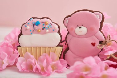 Pastel renkli sevgililer günü kurabiyeleri. Çiçekli zencefilli ayı kurabiyesi. Doğum günü, Kadınlar Günü ya da Sevgililer Günü tebrik kartı şablonu. Pembe arka planda zencefilli kek. Tatlı hediye.
