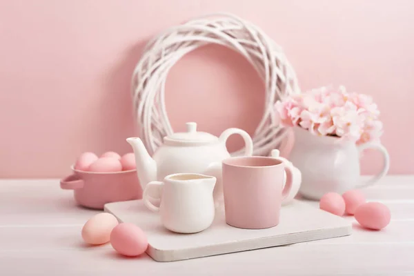 Easter table setting. Tea set and easter eggs on pink background. Spring and Easter holiday concept with copy space. Template Easter Greeting Card. Easter eggs and flowers. Easter decoration.