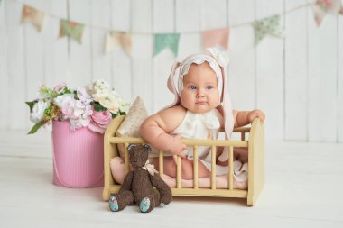 Tavşan kulaklı şirin bir bebek. Paskalya tebrik kartı, metnin için kopyalama alanı. Paskalya tatili için poster. Paskalya tavşanı. Anneler Günü için tebrikler. Paskalya tavşanı. Sevimli kız 6 aydır yatakta.