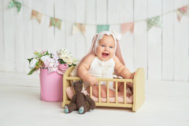 Tavşan kulaklı şirin bir bebek. Paskalya tebrik kartı, metnin için kopyalama alanı. Paskalya tatili için poster. Paskalya tavşanı. Anneler Günü için tebrikler. Paskalya tavşanı. Sevimli kız 6 aydır yatakta.