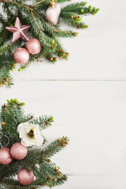 Noel kompozisyonu. Tahta beyaz arka planda firavun dalları. Düz konum, üst görünüm, kopyalama alanı. Noel natürmortdur. Noel çerçevesi köknar dalları ve pembe oyuncaklardan oluşur. Tebrik kartı. Mutlu yıllar.