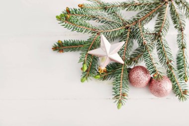 Noel kompozisyonu. Tahta beyaz arka planda firavun dalları. Düz konum, üst görünüm, kopyalama alanı. Noel natürmortdur. Noel çerçevesi köknar dalları ve pembe oyuncaklardan oluşur. Tebrik kartı. Mutlu yıllar.