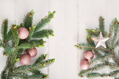 Noel kompozisyonu. Tahta beyaz arka planda firavun dalları. Düz konum, üst görünüm, kopyalama alanı. Noel natürmortdur. Noel çerçevesi köknar dalları ve pembe oyuncaklardan oluşur. Tebrik kartı. Mutlu yıllar.