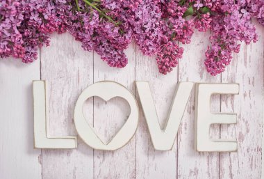 Tahta mektuplar ve leylak çiçeklerinden yapılmış bir mesaj. Mutlu yıllar. Merhaba bahar ve yaz. Kadınlar Günü ve Anneler Günü için tebrik kartı. Sezon, kopyalama alanı. Romantik geçmiş.