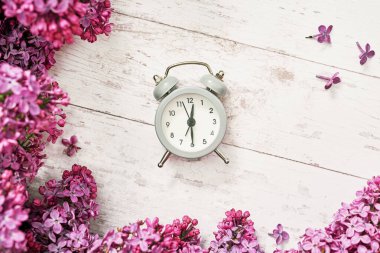 Günaydın konsepti. Sıcak bir sabah. Alarm saatini ve leylak çiçeklerini kapat. Doğum günün kutlu olsun. Merhaba bahar ve yaz. Kadınlar ve anneler günü için tebrik kartı. Bahar mevsimi, kopyalama alanı