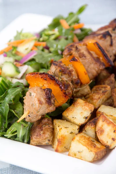 Pork kebab skewer dish with potatoes and salad — Stock Photo, Image