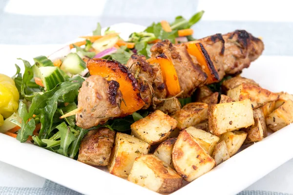 Pork kebab skewer dish with potatoes and salad — Stock Photo, Image