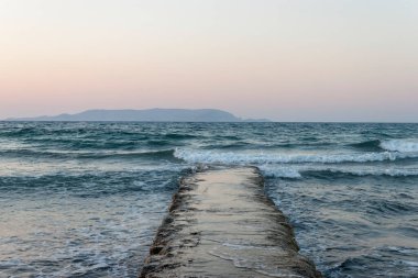 Deniz manzaralı, eski bir rıhtım ve alçak dağ manzaralı. Kokkini Hani, Girit, Yunanistan. Akşamları deniz manzarası.