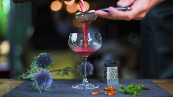 Der rote Cocktail ergießt sich ins Glas. Barmann gießt einen roten Cocktail ins Glas. Das Glas steht auf dem Tisch, auf dem der alkoholische Cocktail ausgeschenkt wird. Food Styling Restaurant