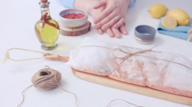 Beyaz masada bir yemek stili var. Ellerin balığın içinde olduğu bohçayı çözsün. Birisi halatı bir tabağa koyuyor..