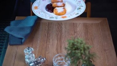 Garson tabağı peynirli kekle masaya koyuyor. Birisi restorana yemek getiriyor. Bir restoranda kahvaltı servisi. Kahvaltını kafede yap..