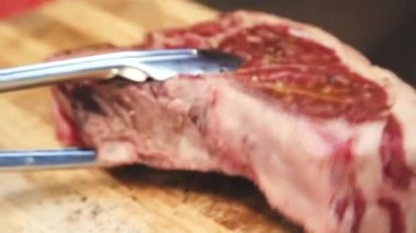 Şef barbekü etini terbiye ediyor. Birisi biftek yapıyor. Şef kızartma için biftek yapıyor..