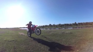 Adam ormanda tarlada motosiklet sürüyor. Tehlikeli motosiklet sürüşü. Spor bisikleti