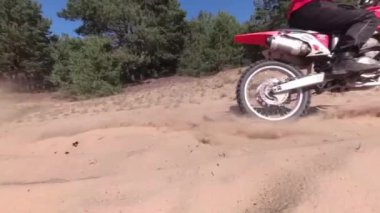 Adam kumda motosikletle geziyor..